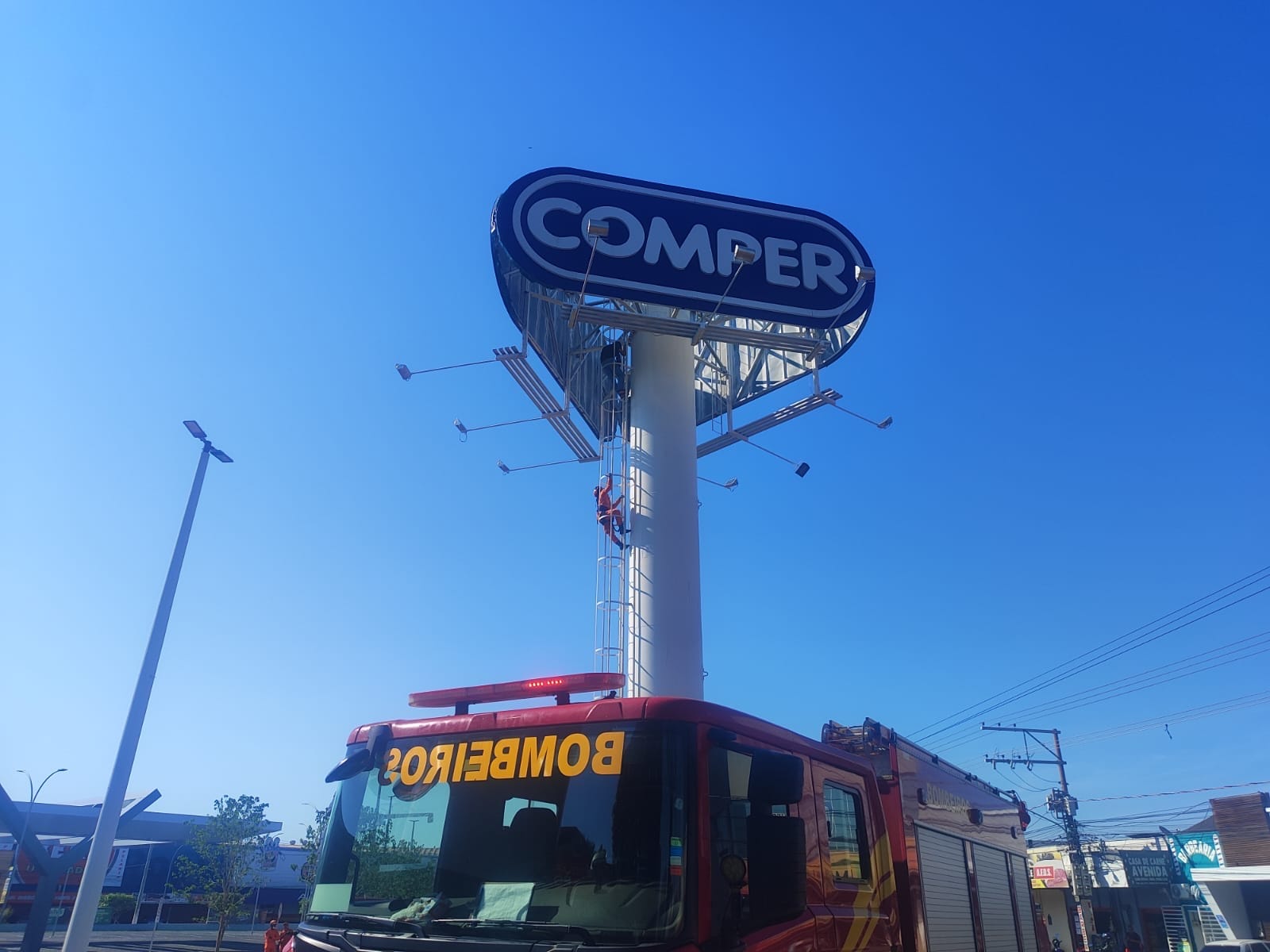 Homem sobe em placa de publicidade na Alzira Santana em Várzea Grande; bombeiros tentam convencê-lo a descer